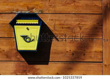 Yellow metal mailbox on a wooden wall