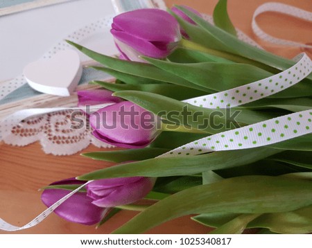 Purple tulips with a picture frame in the background laying on a wooden table, Spring flowers