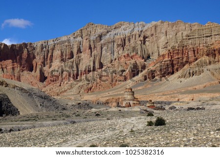 Buddhist  chorten against the background of red cliffs of Drakmar. Trekking to the closed zone of Upper Mustang. Nepal.