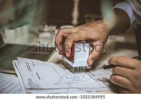 Businessman hand approve document using company stamp. 