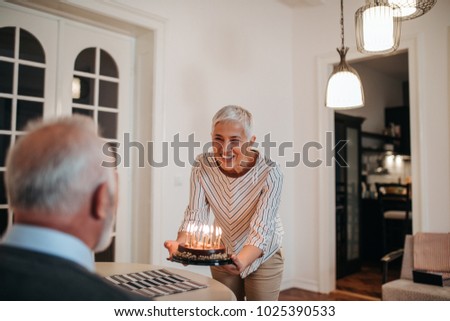 Mature woman surprising her husband with a birthday cake