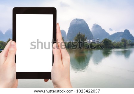 travel concept - tourist photograps water of Yulong and Jinbao rivers and karst peaks in Yangshuo County in China in spring on tablet with cut out screen for advertising logo