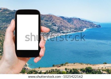 travel concept - tourist photographs Letojanni resort town on beach of Ionian Sea near Taormina city in Sicily Italy in summer season on smartphone with cut out screen for advertising logo