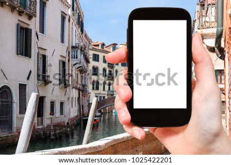 travel concept - tourist photograps houses and canal in Venice city in Italy in spring on smartphone with cut out screen for advertising logo