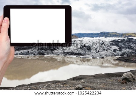 travel concept - tourist photographs Solheimajokull glacier (South glacial tongue of Myrdalsjokull ice cap) in Katla Geopark in Iceland in autumn on tablet with cut out screen for advertising logo