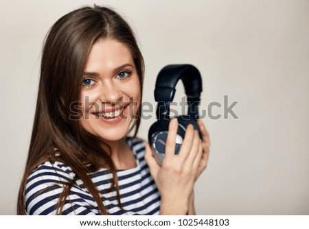 Smiling young woman listening music with earphones. Smile with teeth. Isolated portrait.