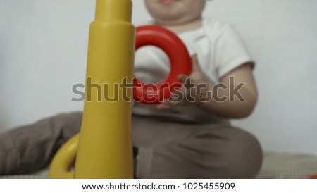 Little baby (boy), sits playing toy pyramid, white background. Concept: babies, fair skin, beautiful children.