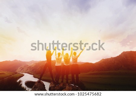 Group happy friends up hand on background mountains, sunset