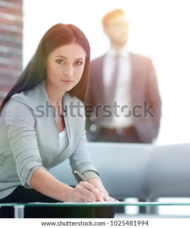 business woman signs documents in a modern office.