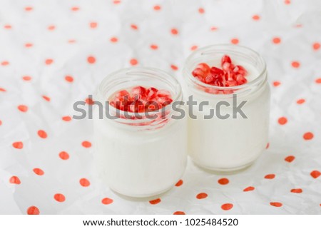 
homemade yogurt with pomegranate seeds in jars on a napkin in polka dots