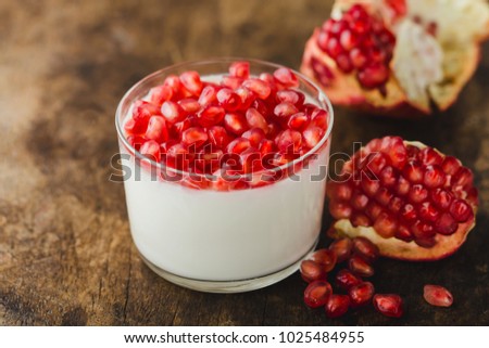 
homemade yogurt with pomegranate seeds in jars on an old wooden table