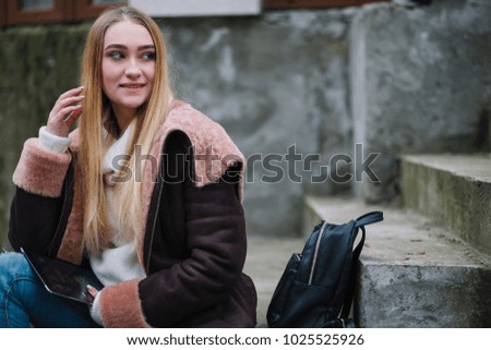 young blond girl with tablet walking on the street 