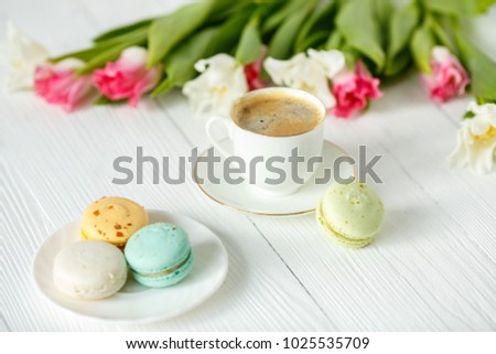 Coffee, pink and white tulips and macarons on the white wooden table. Breakfast. Coffee break.