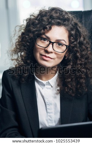 portrait of a curly-haired female teacher wearing glasses.