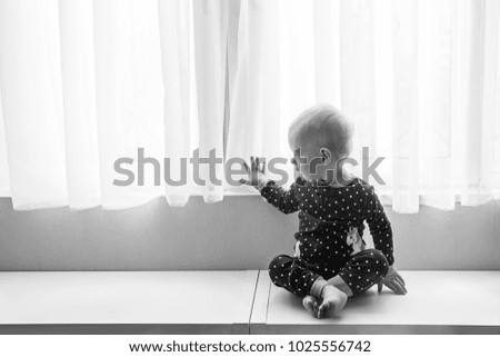 a small child on a window sill near a window in pajamas with a unicorn