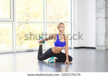 Blonde activity woman in yoga posture, king pigeon, one legged. Indoor shot