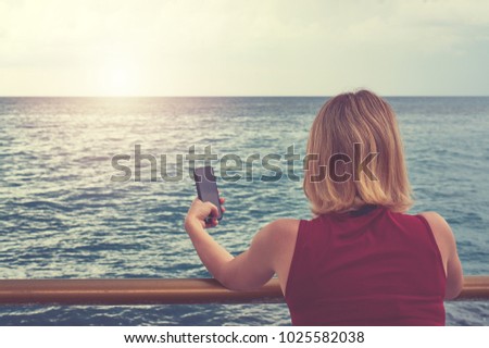 young women stand alone hold mobile phone for photography sea.