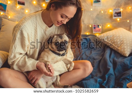Young woman weekend at home decorated bedroom holding paw of dog