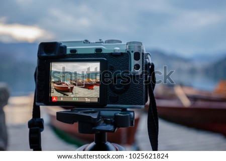 Modern MILC camera on a tripod shooting outdoors photograpy Royalty-Free Stock Photo #1025621824