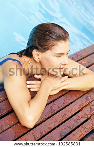 Elderly attractive woman relaxing at edge of swimming pool