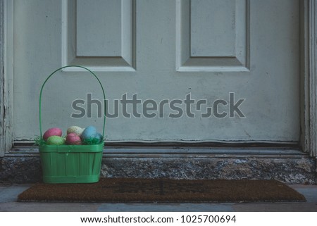 Basket full of Easter eggs framed on the left outside in front of the door