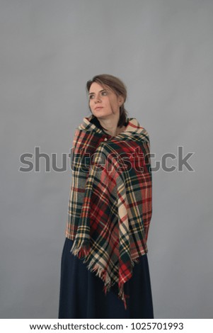 young beautiful girl posing in studio in checkered scarf is standing