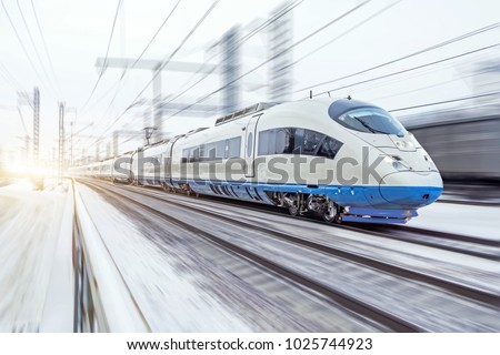 High-speed train rides at high speed in winter around the snowy landscape Royalty-Free Stock Photo #1025744923