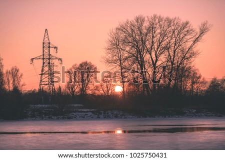 colorful winter sunset with trees and power lines in background and ice blocks - vintage retro effect