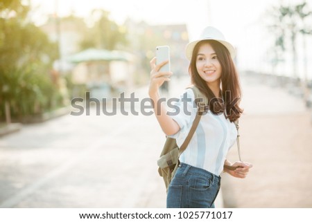 Young beautiful female traveler in the city and using smart phone for take a photo