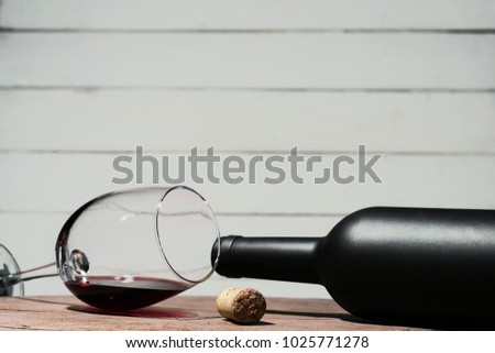 Glass of wine A black bottle of red wine on a wooden table. Beautiful white wooden background