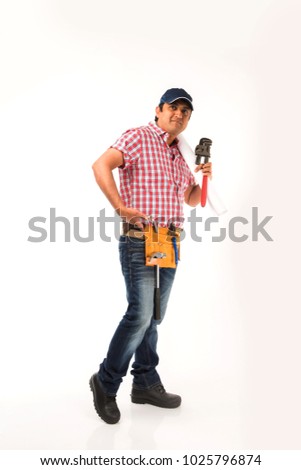 Indian plumber holding drawing roll and Pipe wrench or plumbing spanner, standing isolated over white background
