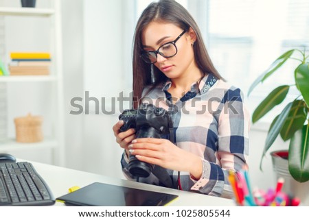 pretty young woman photographer with camera in office