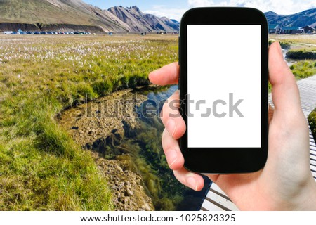 travel concept - tourist photographs Landmannalaugar area of Fjallabak Nature Reserve in Highlands region of Iceland in autumn on smartphone with cut out screen for advertising logo