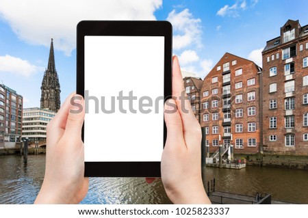 travel concept - tourist photographs houses on waterfront of Nikolaifleet canal in Hamburg city downtown in september on tablet with cut out screen for advertising logo