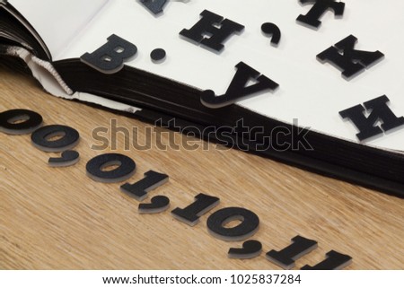 black letters fall out from the book on the oak table as a symbol of the loss of knowledge in the digital world