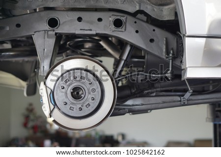 Car service - mechanic unscrewing automobile parts while working under a lifted auto.Disc car close up