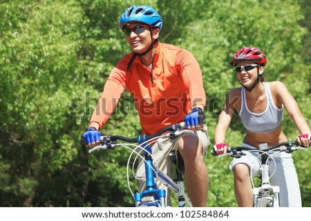 Portrait of a handsome man riding a bike with his wife on background