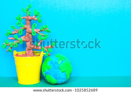 Colorful plasticine tree in a toy bucket and a plasticine globe on the blue background. 