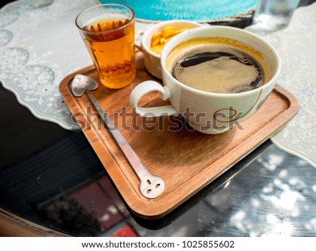 Cup of coffee, Tea and ABC cookies on wooden saucer on table.
