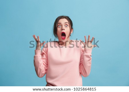 Beautiful female half-length portrait isolated on blue studio backgroud. The young emotional surprised woman standing and looking at camera.The human emotions, facial expression concept. Front view Royalty-Free Stock Photo #1025864815