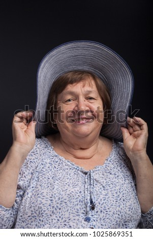 Studio portrait of elderly woman with hat. Smile.