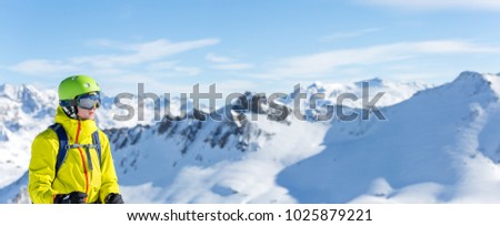 Panoramic image of man in helmet and with snowboard against background of snowy landscape