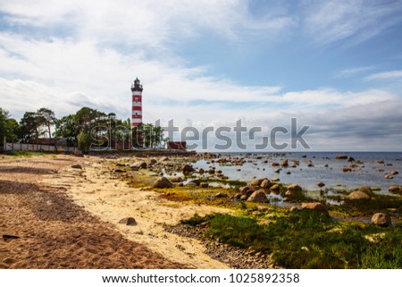 Red and white lighthouse. Rocky seashore Royalty-Free Stock Photo #1025892358