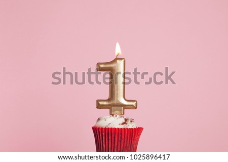 Number 1 gold candle in a cupcake against a pastel pink background Royalty-Free Stock Photo #1025896417