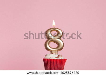 Number 8 gold candle in a cupcake against a pastel pink background Royalty-Free Stock Photo #1025896420