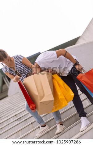 Beautiful happy couple walking in the city holding shopping bags. Couple in the shopping. Urban city shopping concept.