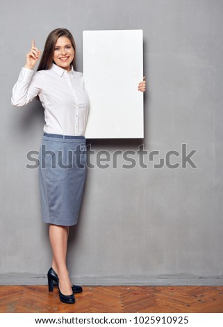 Smiling businesswoman holding big white board for advertising signs and pointing finger up.