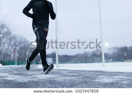 Image of athlete running at stadium in winter