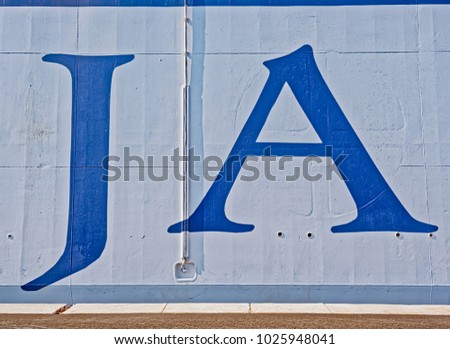 Blue letters on boat moored in harbor on a sunny day.