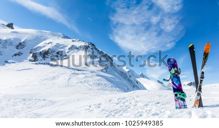 Photo of crossed skis and sticks against background of snowy landscape during day